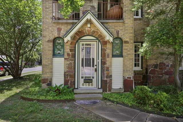 a view of a brick house with a large windows and flower plants