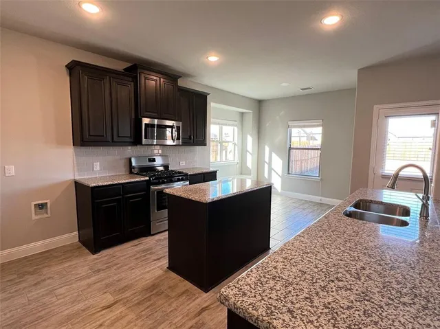 a kitchen with granite countertop wooden cabinets and a stove top oven