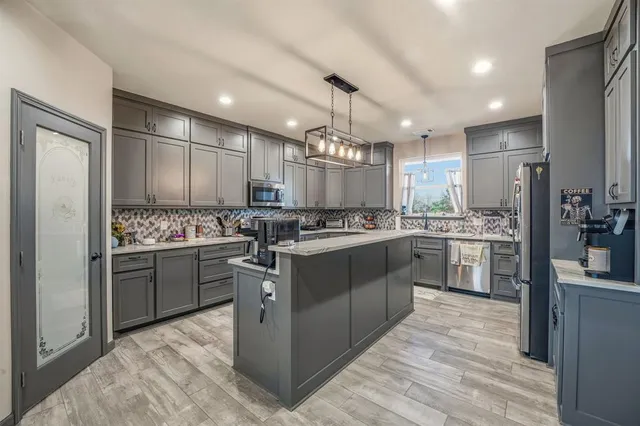 a kitchen with kitchen island granite countertop stainless steel appliances cabinets a sink and a counter top space