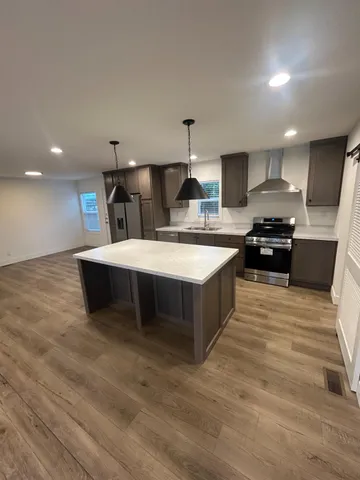 a large kitchen with stainless steel appliances a large counter top a stove and a refrigerator