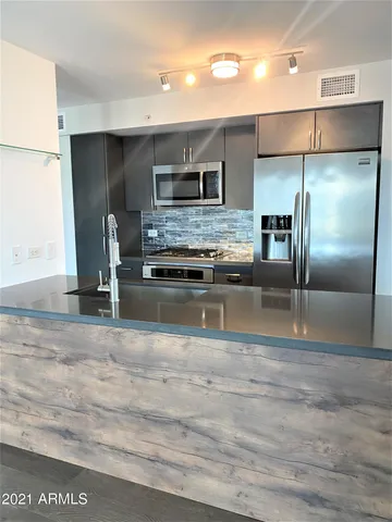 a kitchen with kitchen island stainless steel appliances a sink refrigerator stove and microwave