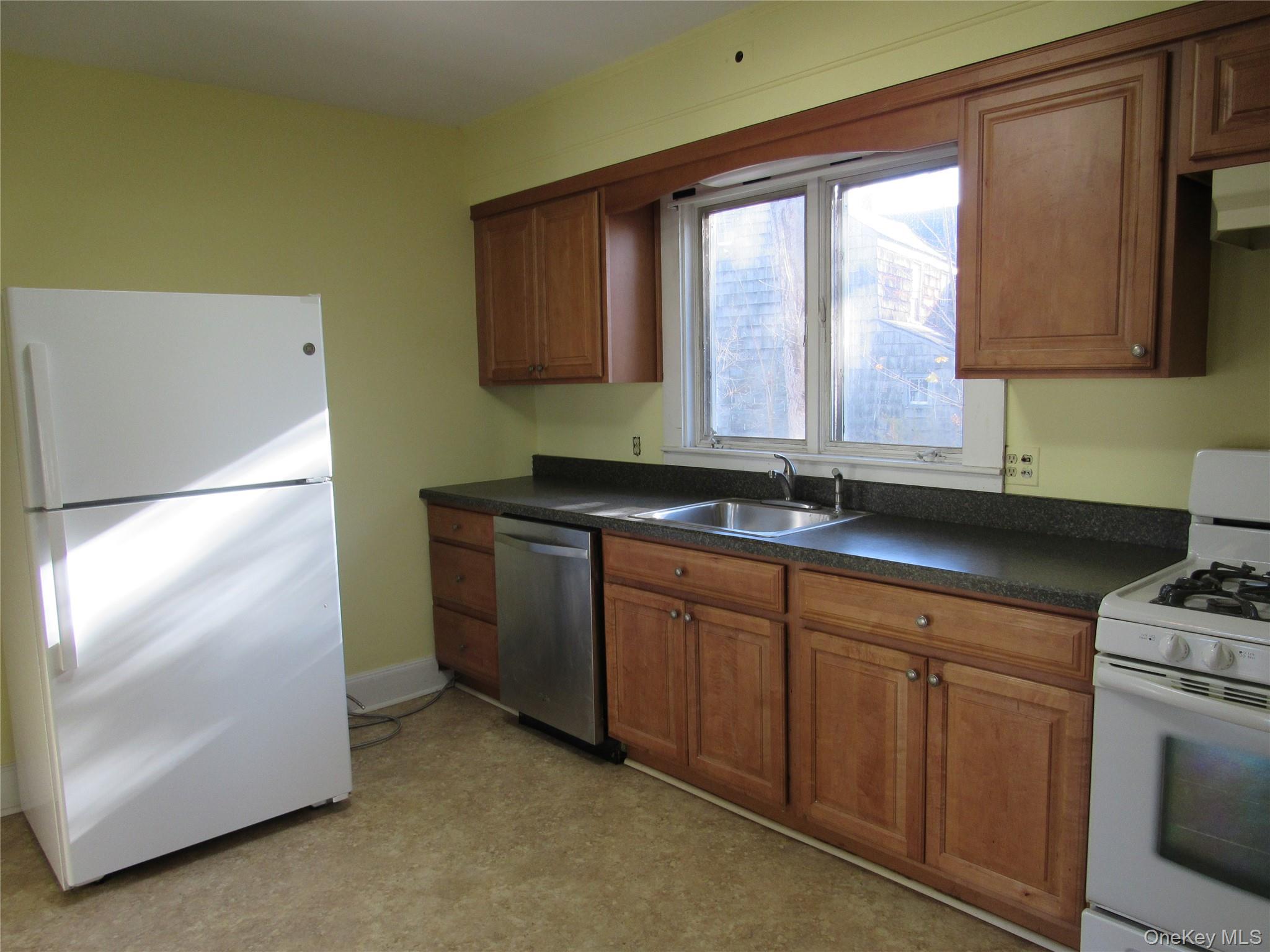 98 Main Street Chester, NY 10918 - Photo 14 of 32 Kitchen featuring brown cabinetry, white appliances, dark countertops, under cabinet range hood, and light floors