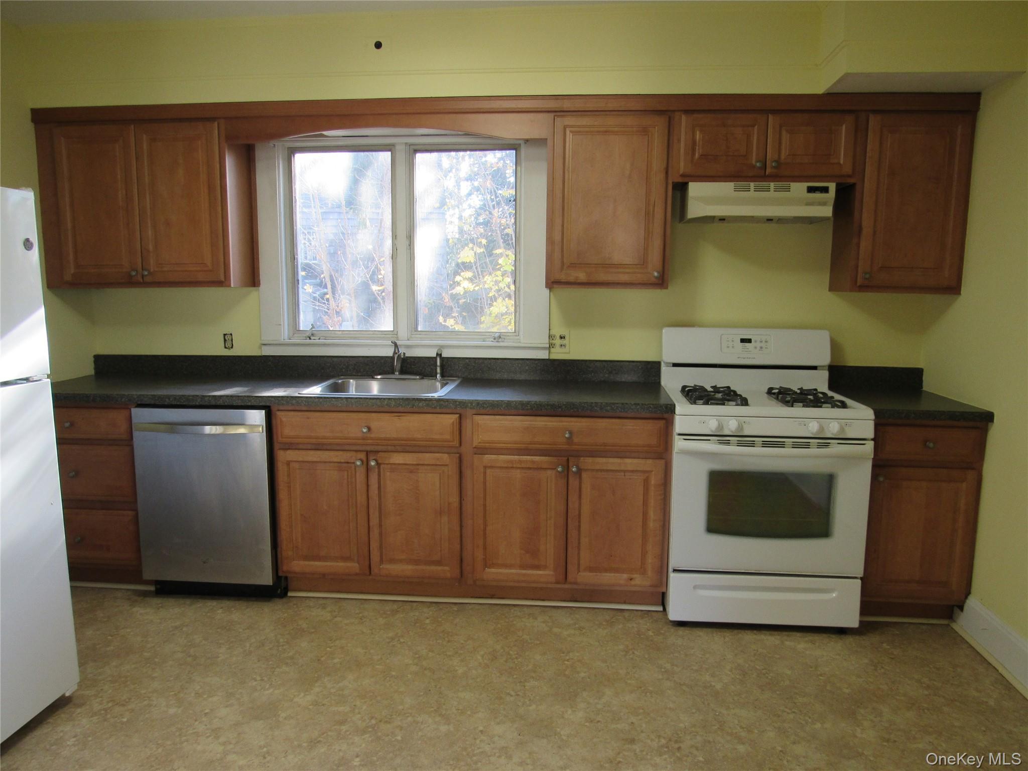 98 Main Street Chester, NY 10918 - Photo 15 of 32 Kitchen with white appliances, brown cabinetry, dark countertops, and under cabinet range hood