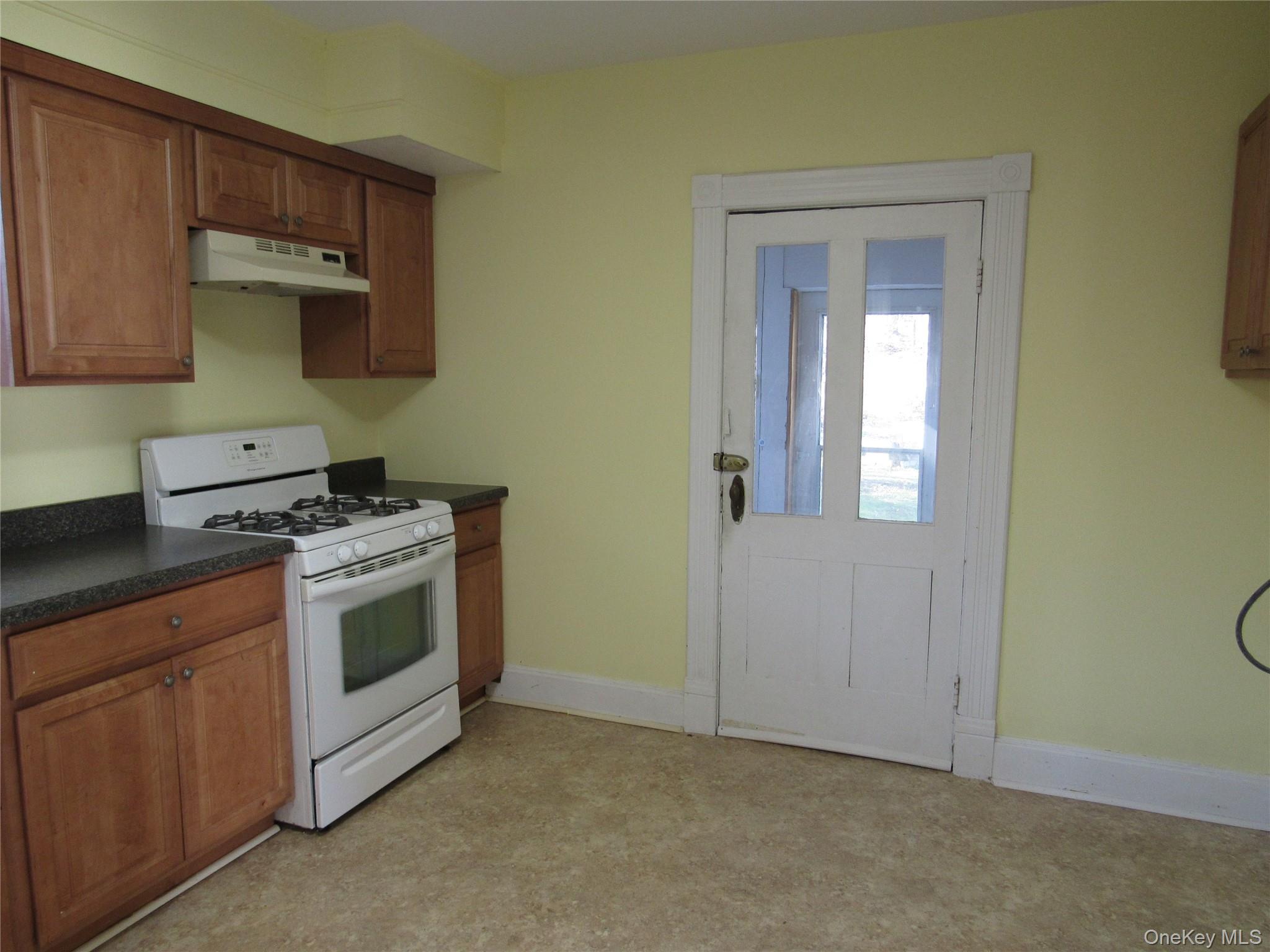 98 Main Street Chester, NY 10918 - Photo 16 of 32 Kitchen with brown cabinetry, white gas stove, dark countertops, and under cabinet range hood