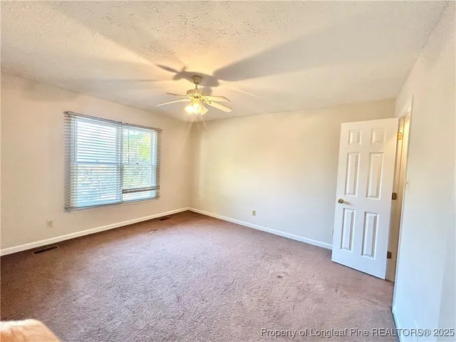 an empty room with a ceiling fan and a window
