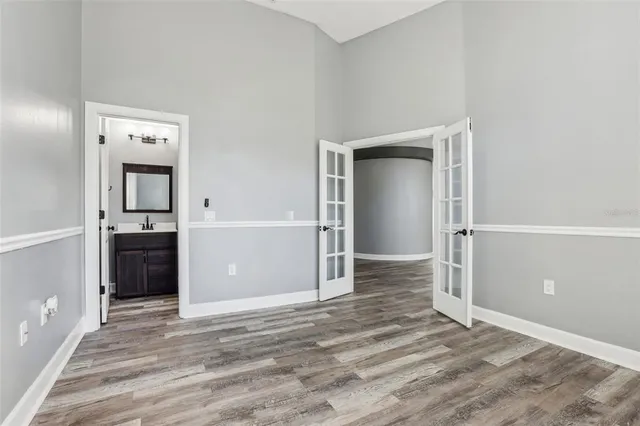 an empty room with wooden floor fan and windows