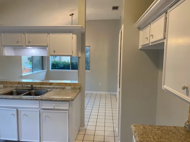 a kitchen with a granite countertop sink and cabinets