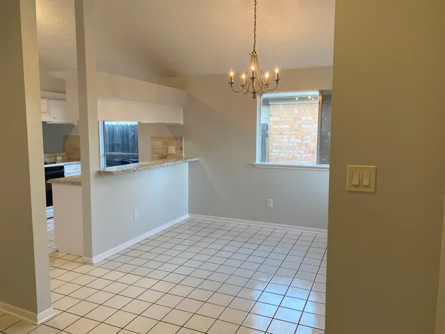 a view of an empty room with window and chandelier