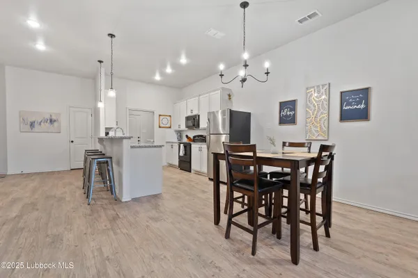 a view of a dining room and livingroom with furniture wooden floor a rug a chandelier
