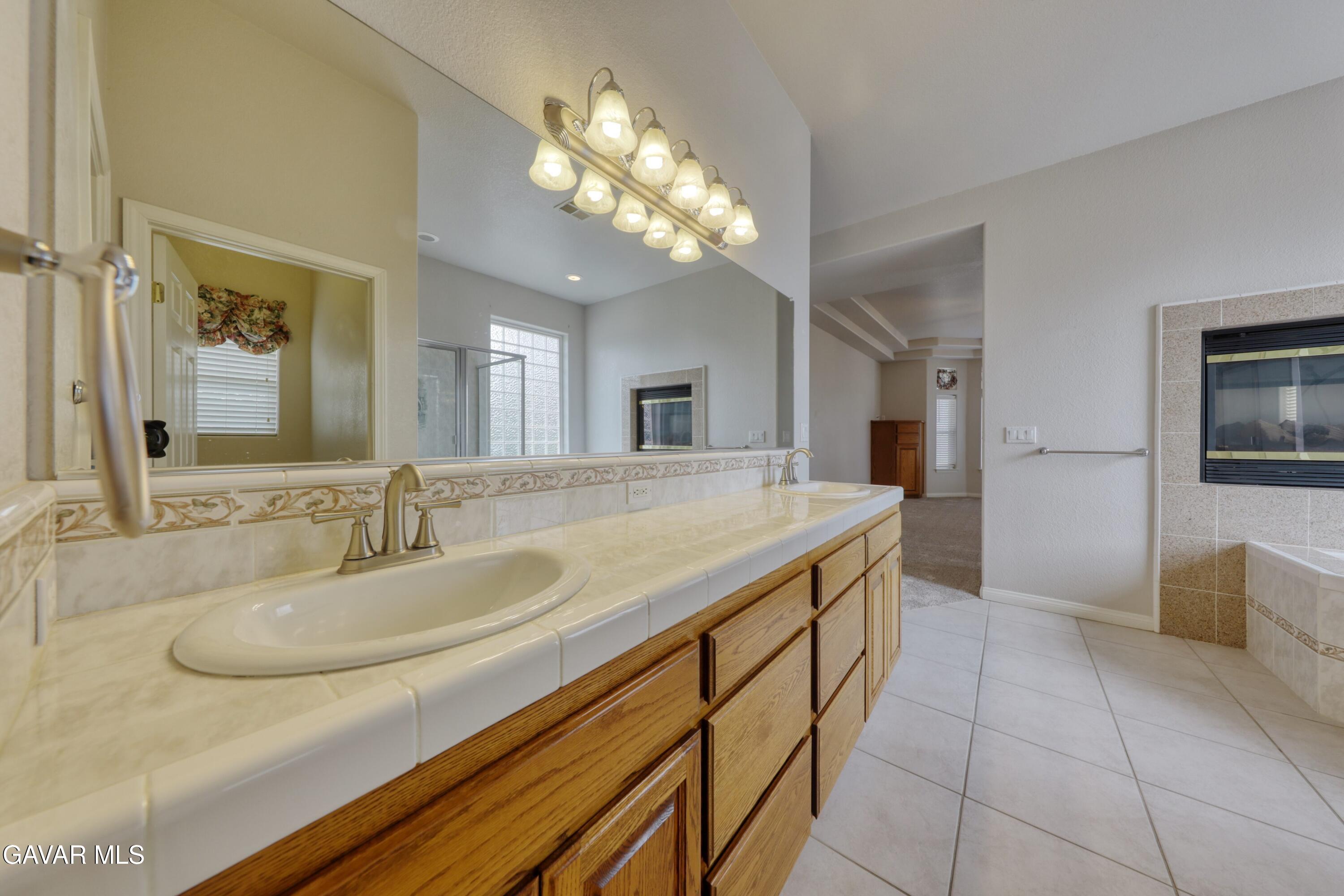 23780 Coyote Court Tehachapi, CA 93561 - Photo 31 of 48 a spacious bathroom with a granite countertop sink a mirror and a shower