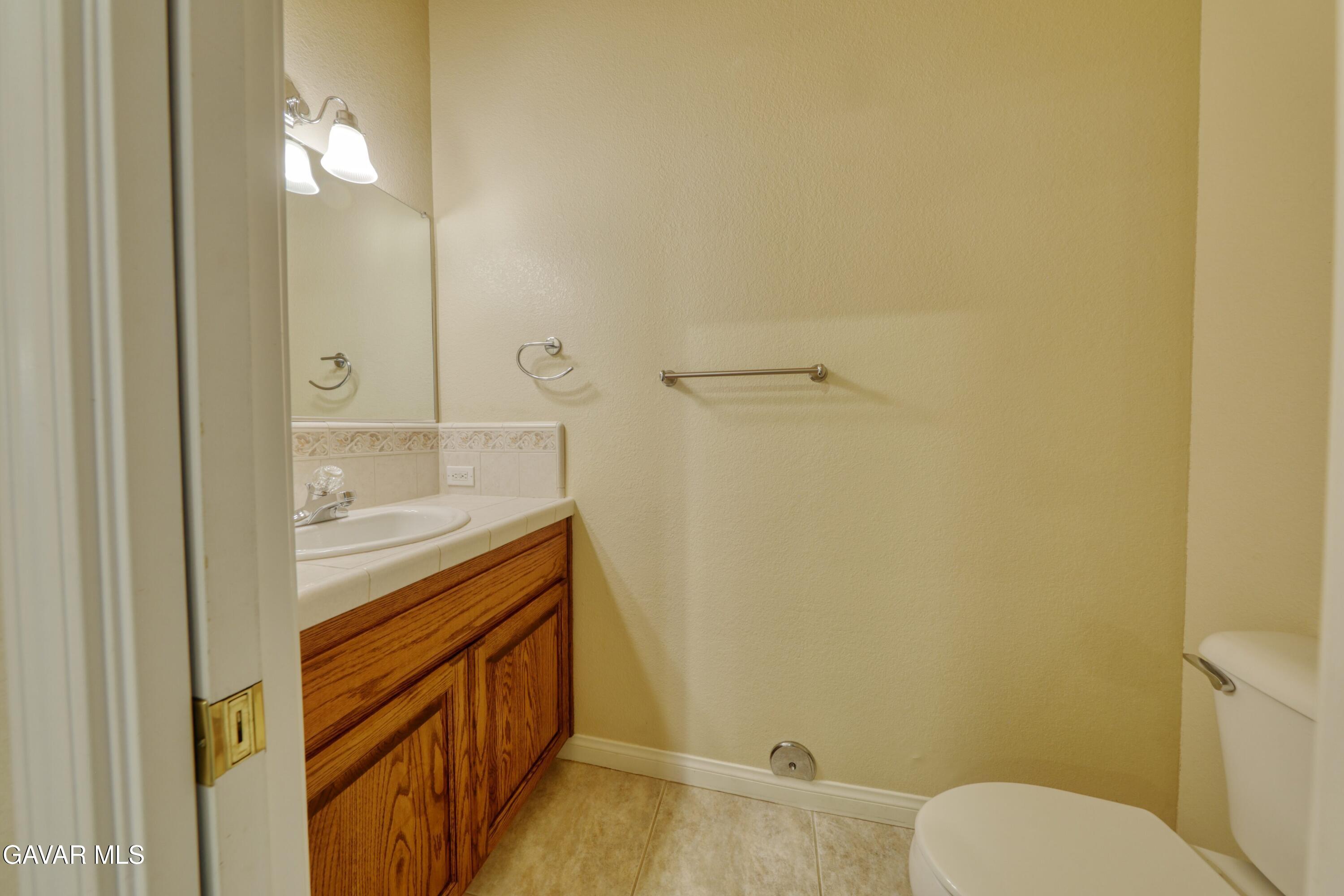 23780 Coyote Court Tehachapi, CA 93561 - Photo 40 of 48 a bathroom with a granite countertop sink mirror vanity and toilet