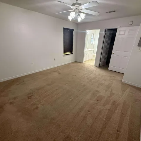 an empty room with closet and a ceiling fan
