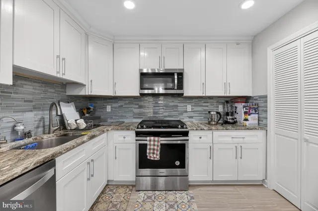 a kitchen with white cabinets and appliances
