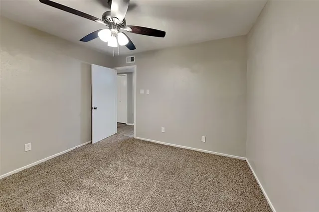 a view of an empty room with a chandelier fan