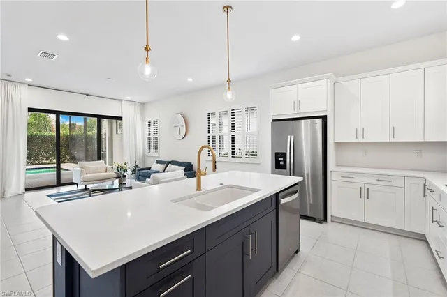 a kitchen with stainless steel appliances granite countertop a sink a refrigerator and a white cabinets