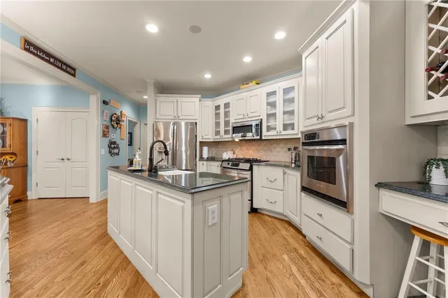 a kitchen with stainless steel appliances granite countertop a stove top oven a refrigerator a sink and dishwasher with wooden floor