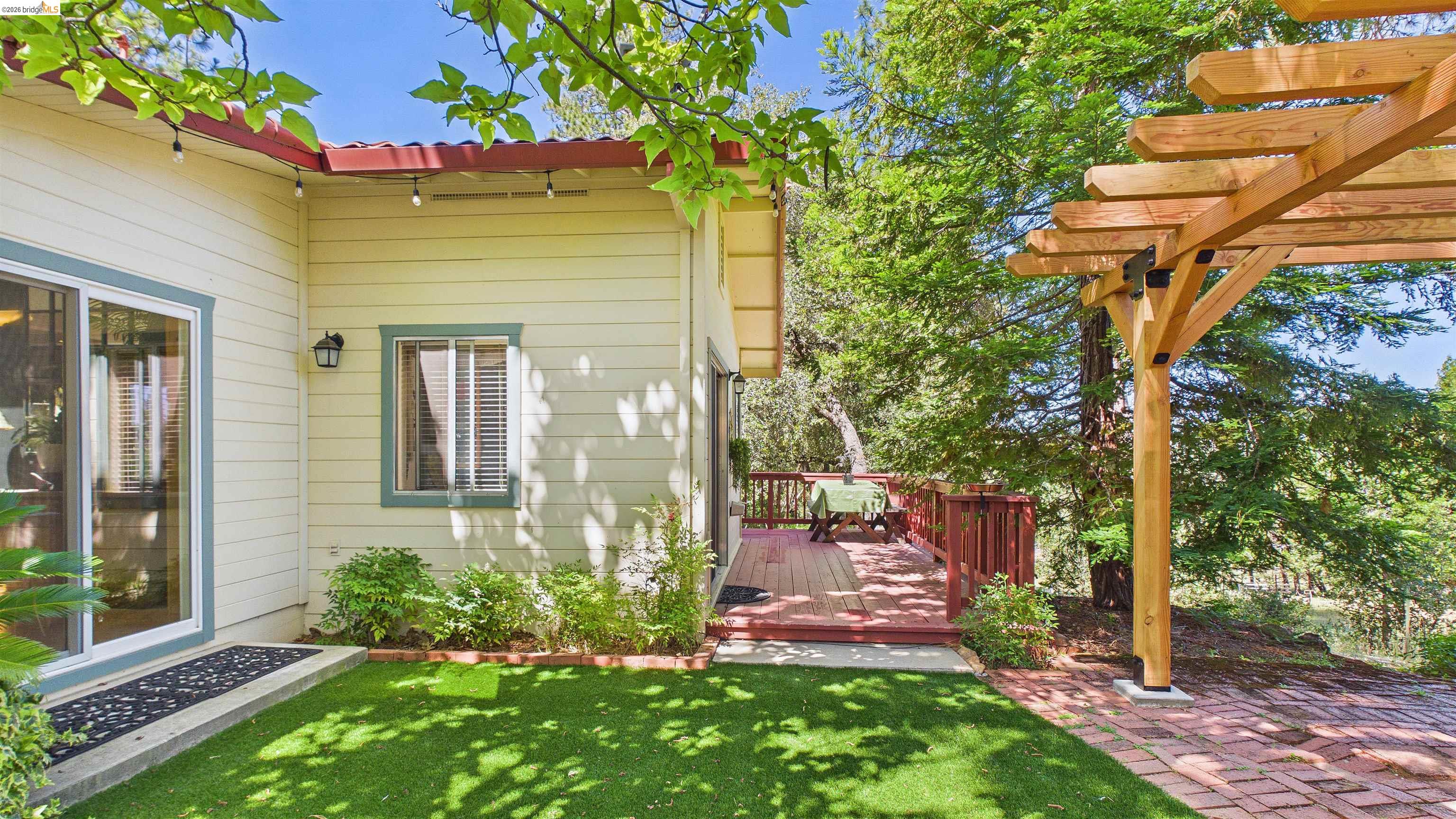 18102 Mt Eaton Road Tuolumne, CA 95379 - Photo 24 of 44 Exterior featuring a wooden pergola, brick paver patio, artificial turf lawn, and a wooden deck