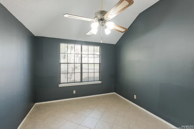 an empty room with windows and chandelier fan