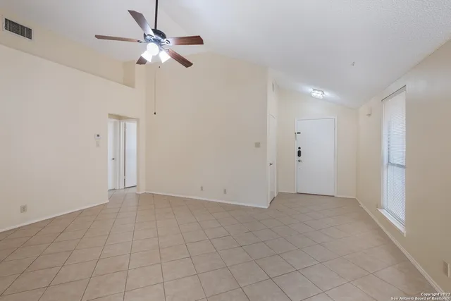 an empty room with white walls and ceiling fan