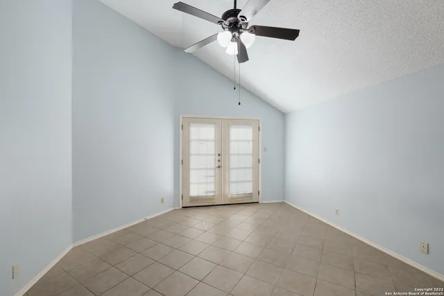 an empty room with chandelier fan and windows