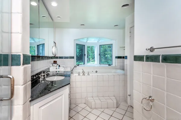 a bathroom with a granite countertop sink a large mirror and shower