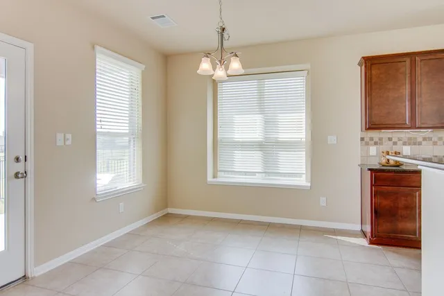 a view of an empty room with a window and cabinet