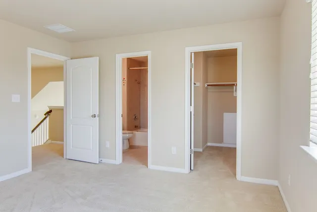 a view of an empty room with closet and a window