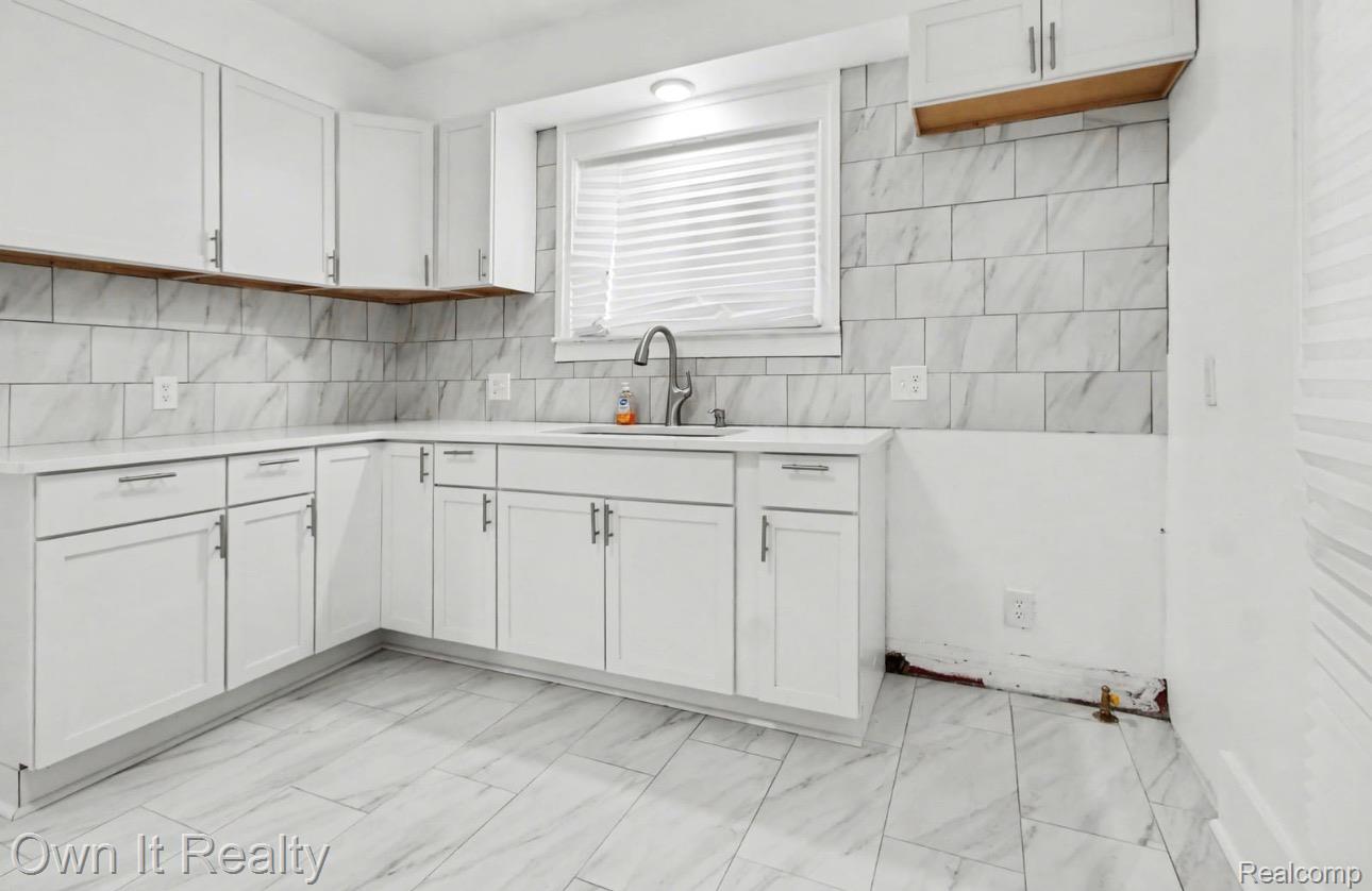 6023 Wayne Road Romulus, MI 48174 - Photo 14 of 25 Kitchen featuring white cabinetry, light marble finish floors, and decorative backsplash