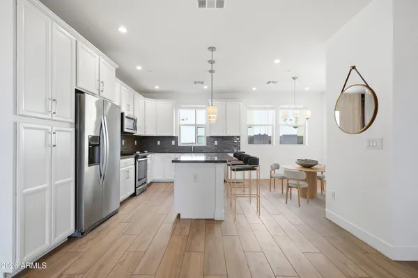 a kitchen with stainless steel appliances a stove a sink a refrigerator and white cabinets with wooden floor