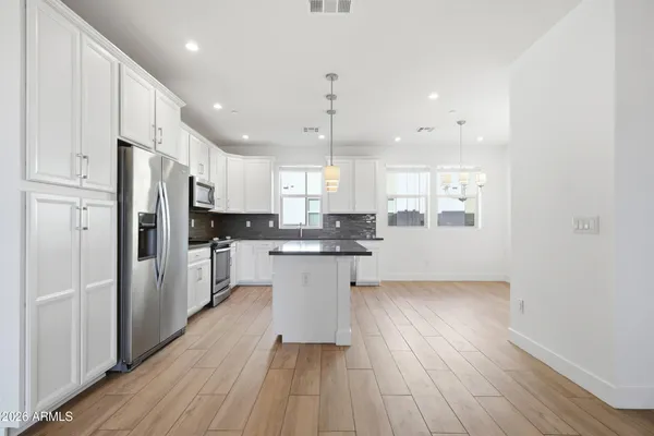 a kitchen with stainless steel appliances granite countertop a refrigerator a sink dishwasher a stove and white countertops with wooden floor