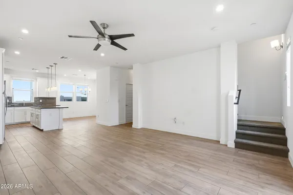a view of an empty room with wooden floor and a kitchen