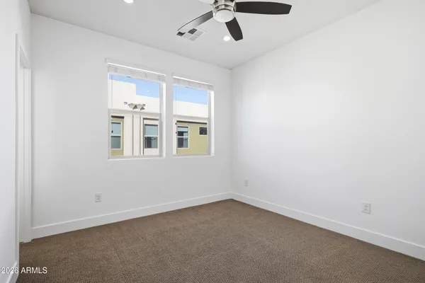 an empty room with windows and ceiling fan