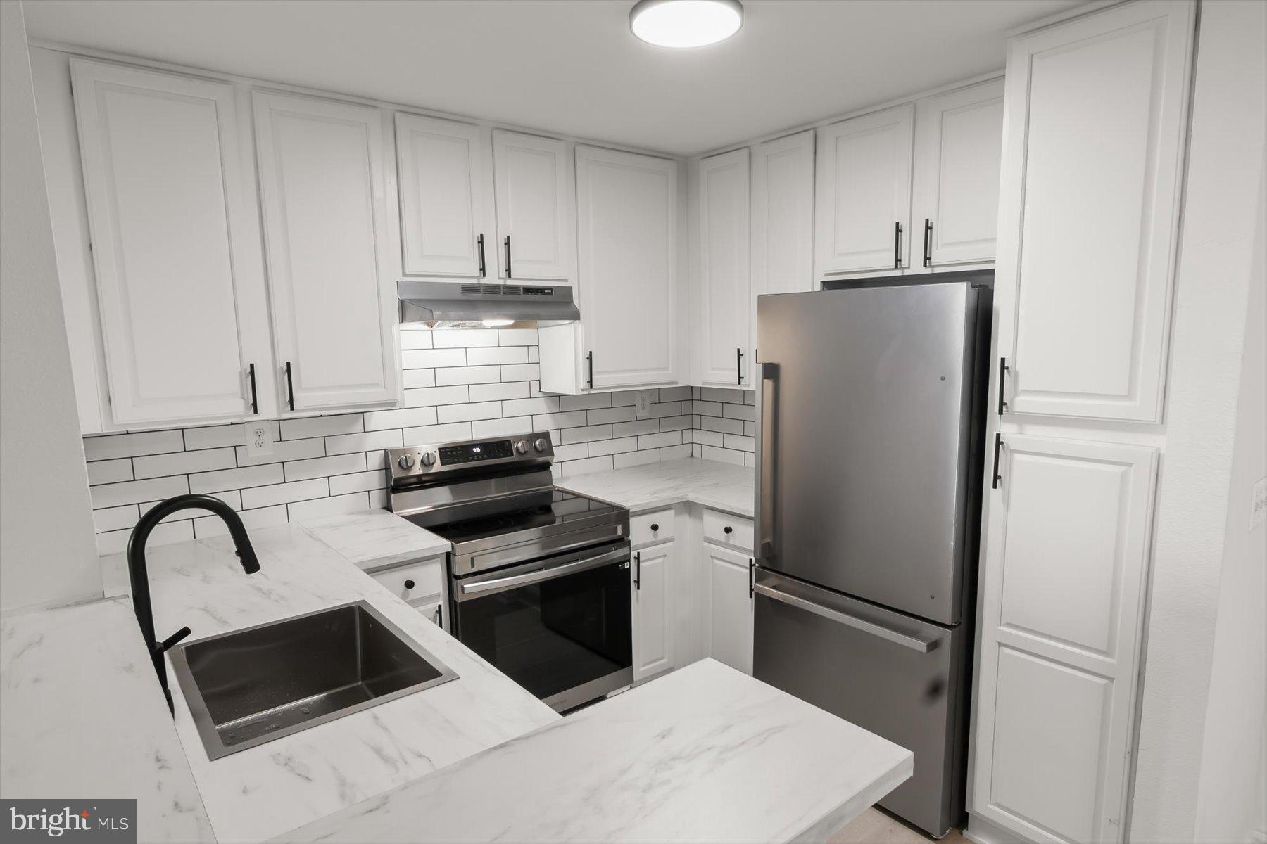 18521 Boysenberry Drive, Unit 242172 Gaithersburg, MD 20879 - Photo 12 of 43 a kitchen with a refrigerator sink and white cabinets