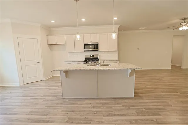 a kitchen with stainless steel appliances kitchen island granite countertop a stove a sink and a refrigerator