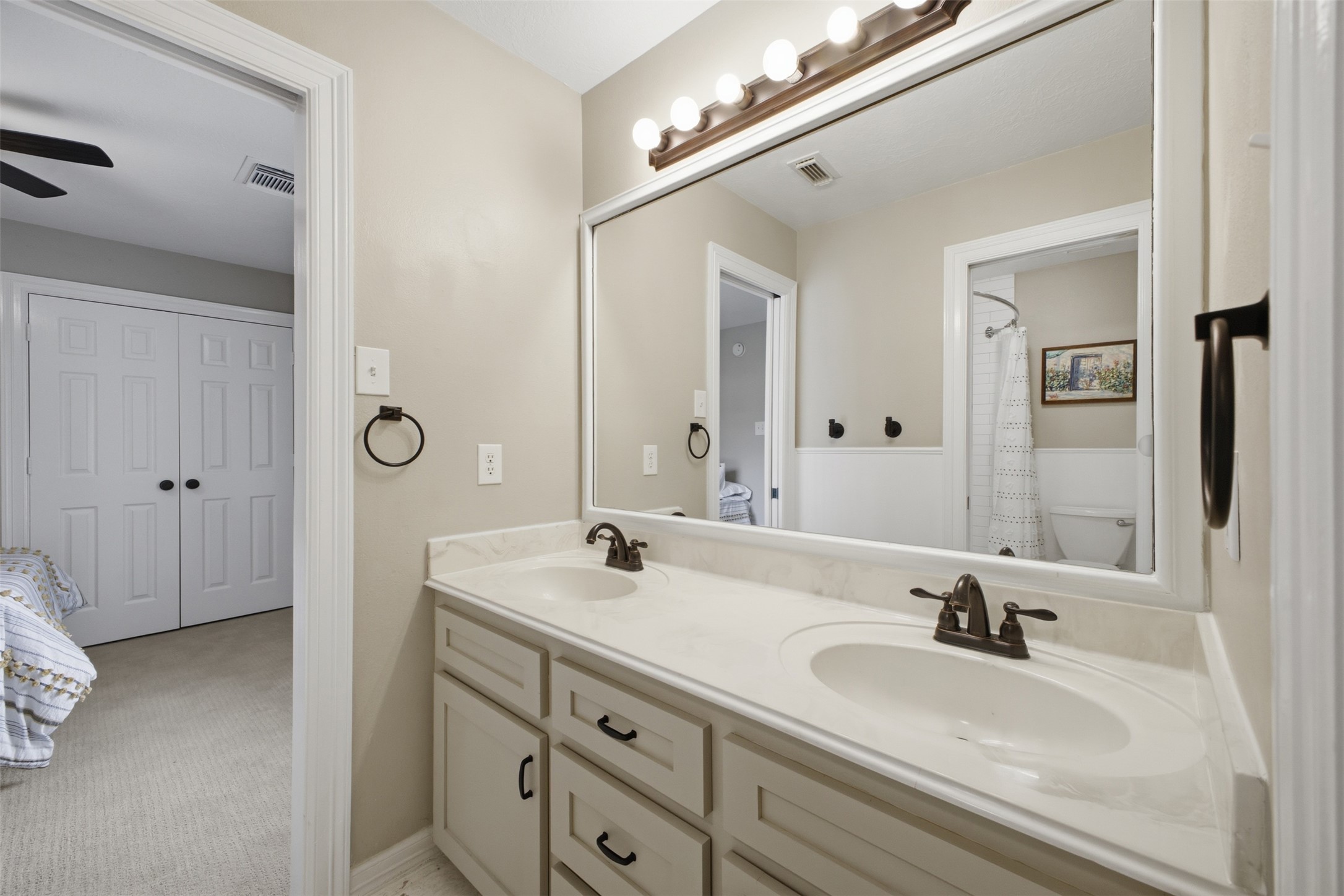 12710 Aries Loop Willis, TX 77318 - Photo 27 of 40 Bathroom vanity featuring a dual sink design, a light-colored countertop, and a large wall-mounted mirror