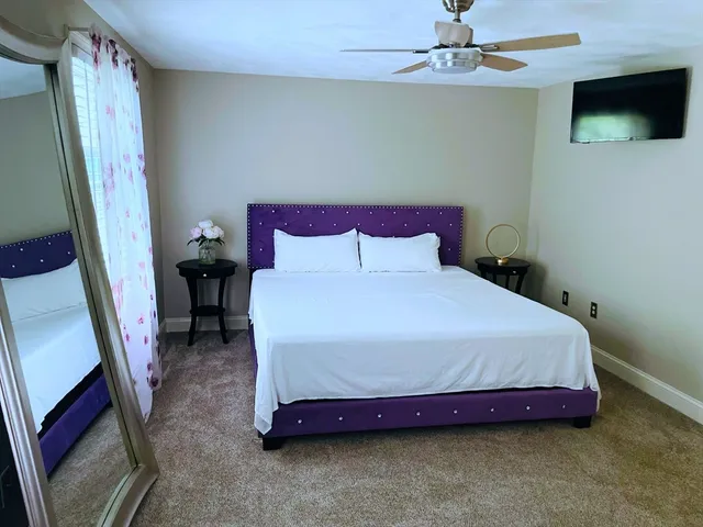 a bedroom with a bed a fireplace and a flat tv screen on the dresser