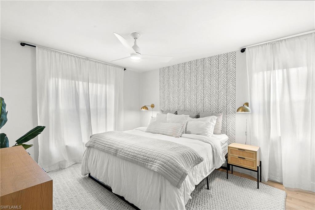 165 Wading Bird Circle, Unit M106 Naples, FL 34110 - Photo 11 of 23 a bedroom with a large bed and a chandelier