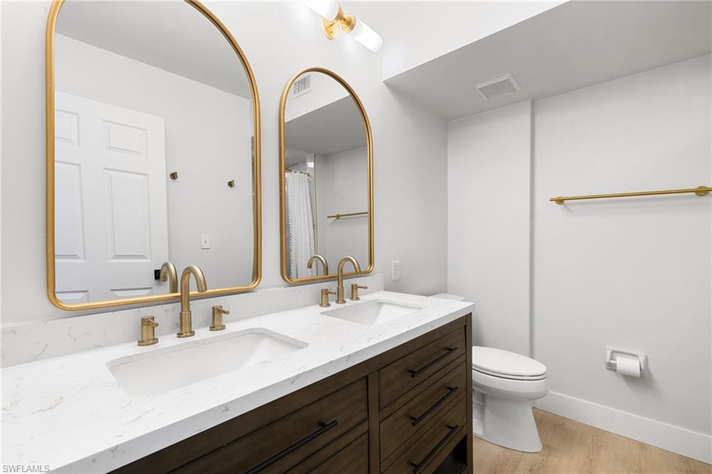 165 Wading Bird Circle, Unit M106 Naples, FL 34110 - Photo 13 of 23 a bathroom with a sink a toilet and a mirror