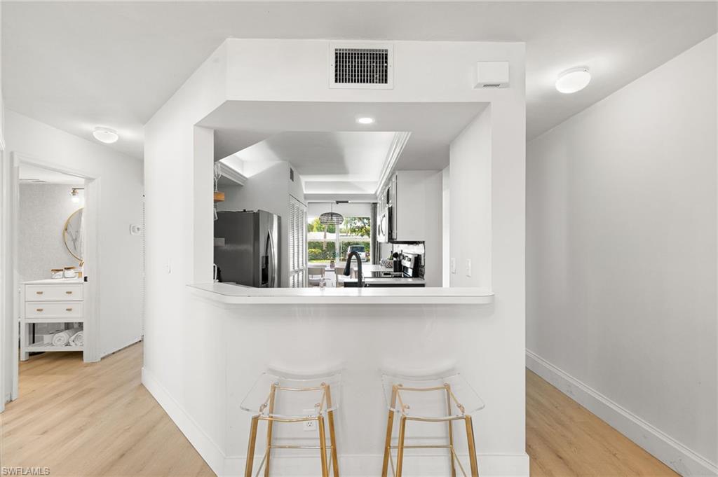 165 Wading Bird Circle, Unit M106 Naples, FL 34110 - Photo 6 of 23 a view of kitchen with furniture and wooden floor