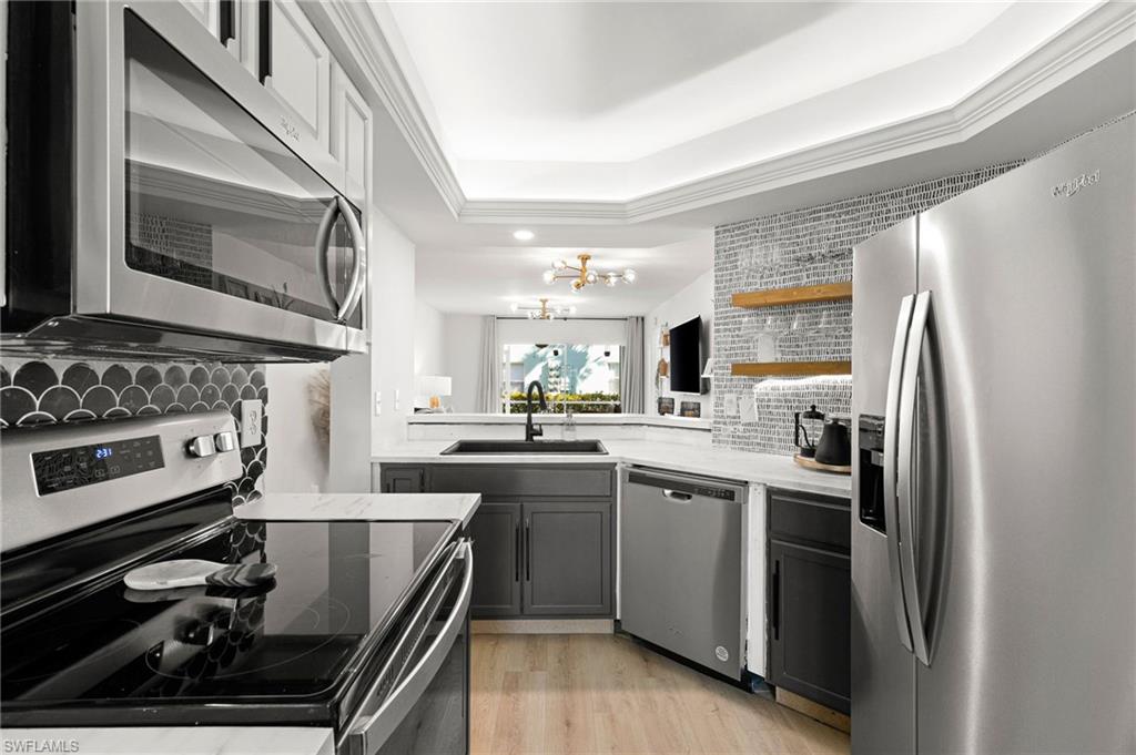 165 Wading Bird Circle, Unit M106 Naples, FL 34110 - Photo 8 of 23 a kitchen with stainless steel appliances granite countertop a sink stove and refrigerator