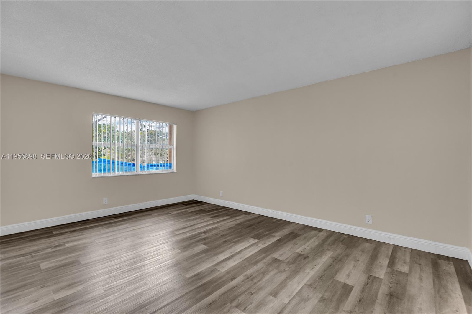17901 Northwest 68th Avenue, Unit T206 Hialeah, FL 33015 - Photo 16 of 27 an empty room with wooden floor and windows