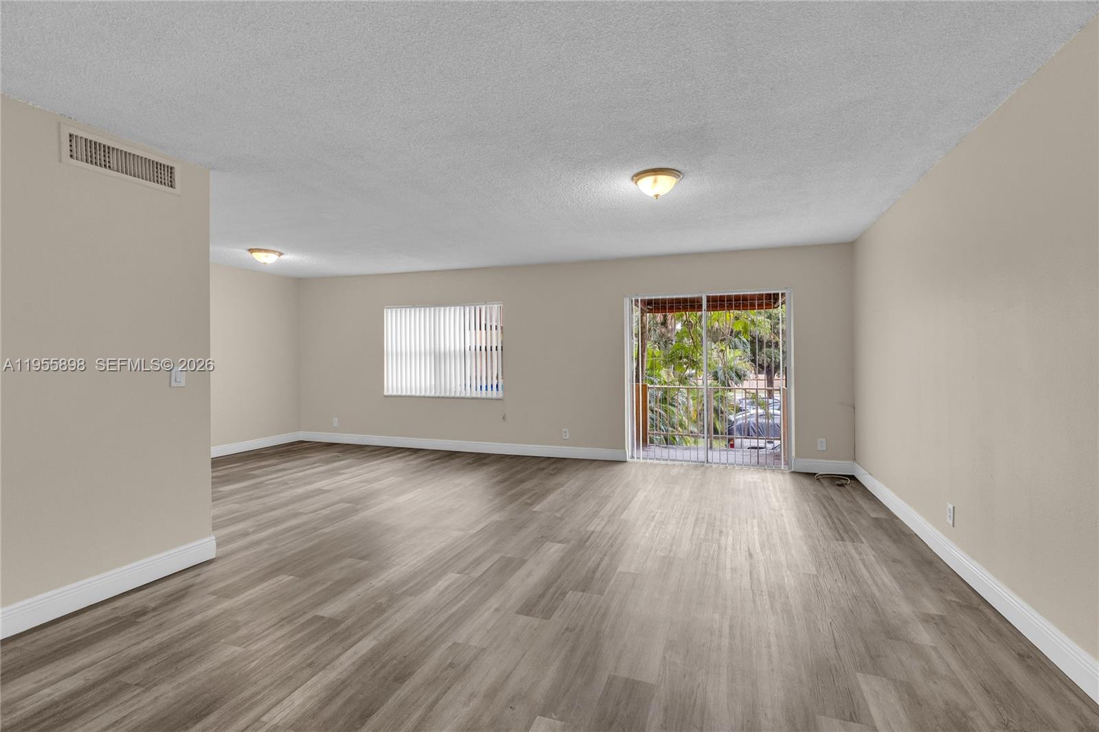 17901 Northwest 68th Avenue, Unit T206 Hialeah, FL 33015 - Photo 4 of 27 an empty room with wooden floor and windows