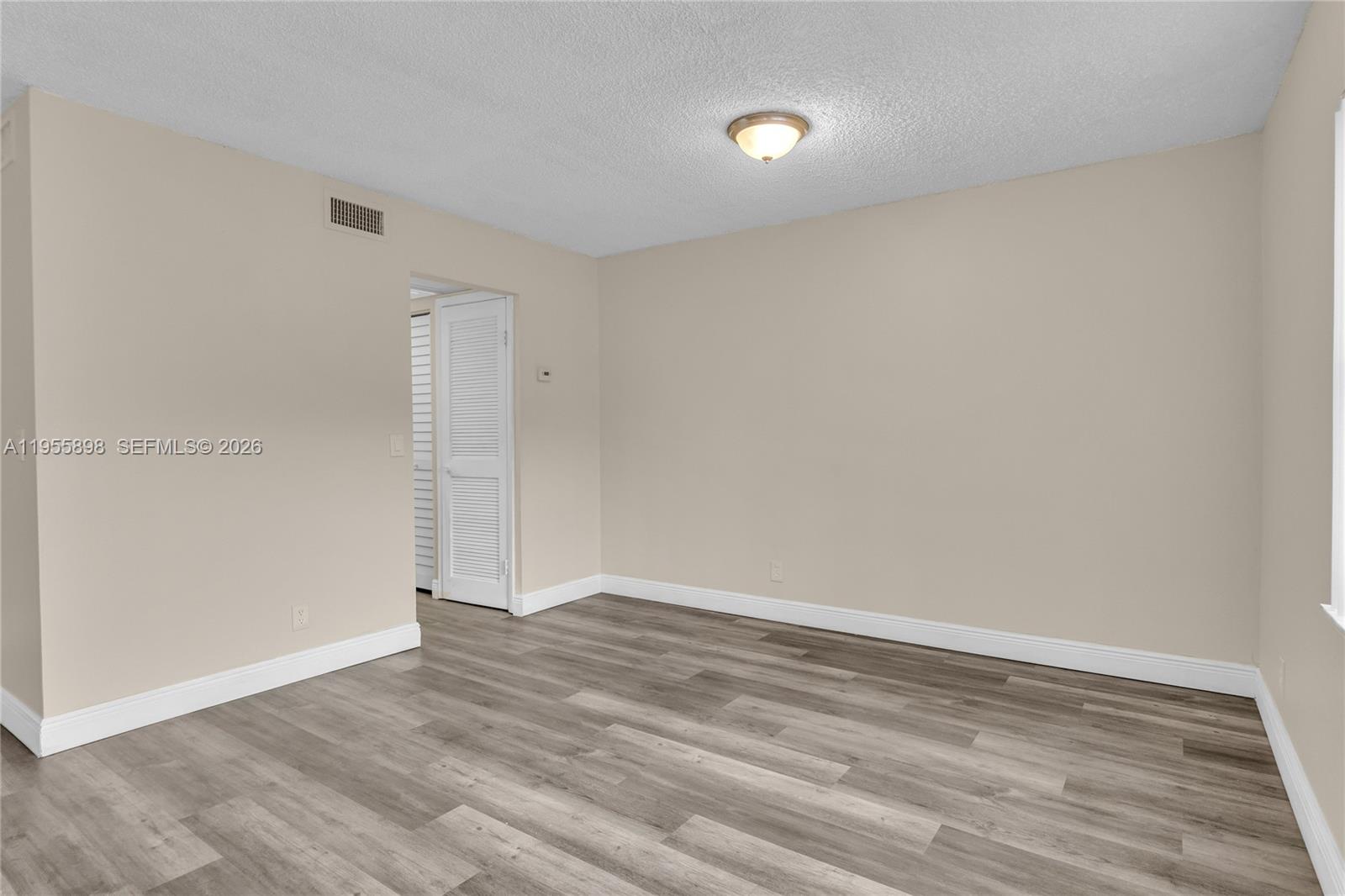 17901 Northwest 68th Avenue, Unit T206 Hialeah, FL 33015 - Photo 5 of 27 a view of an empty room with wooden floor