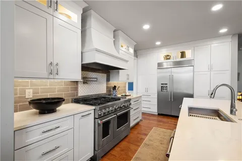a kitchen with stainless steel appliances granite countertop a sink a stove and a refrigerator