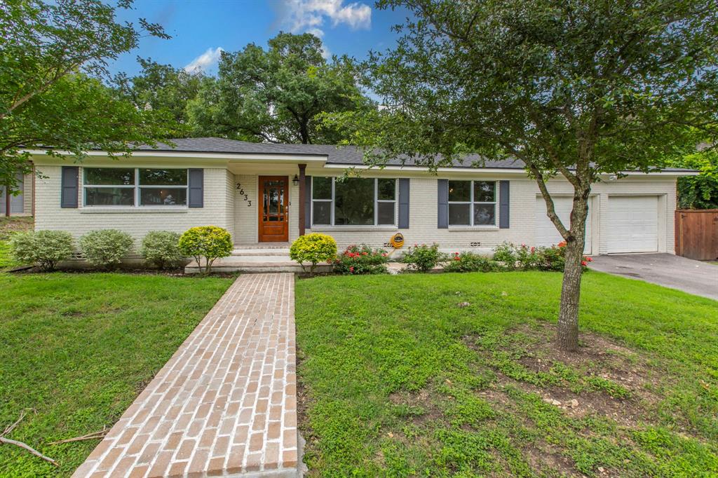 Ranch-style home featuring a garage, asphalt driveway, a front lawn, and brick siding