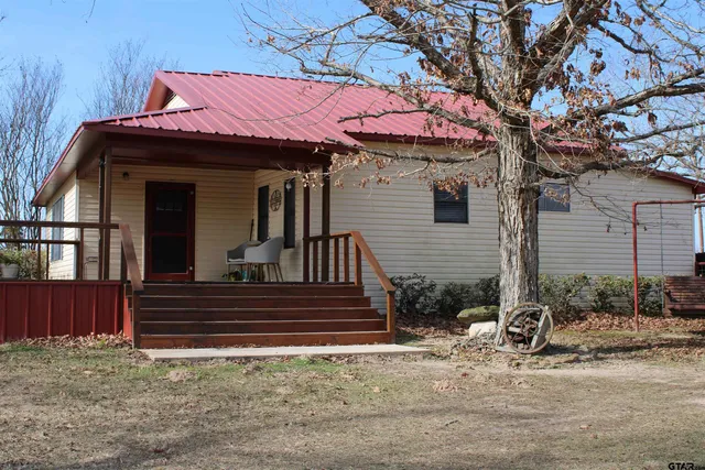 a view of a house with a small yard and large tree