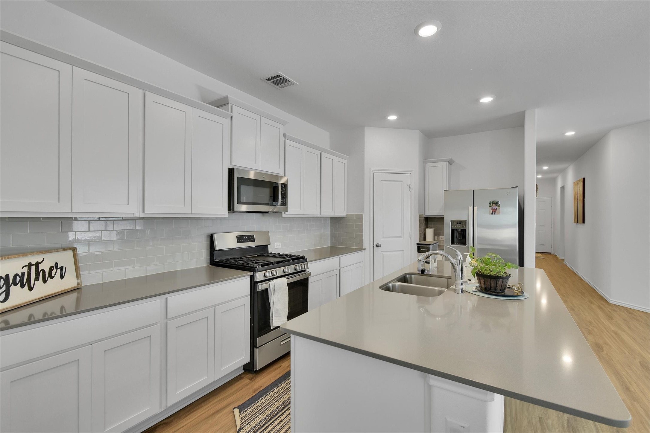 1621 Brueggerhoff Road Leander, TX 78641 - Photo 10 of 28 Kitchen with white cabinets, stainless steel appliances, an island with sink, sink, and light wood-type flooring