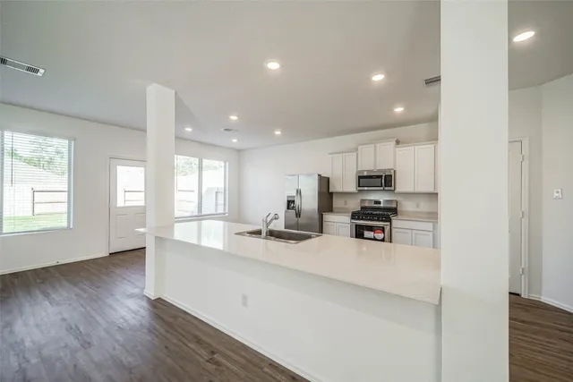 a kitchen with stainless steel appliances a sink a stove a microwave a center island and cabinets