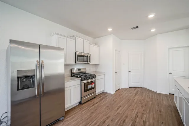 a kitchen with stainless steel appliances a refrigerator and a hard wood floor