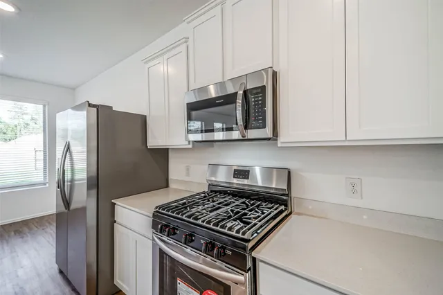 a kitchen with stainless steel appliances white cabinets and a stove top oven